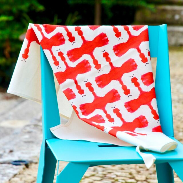 torchon avec des motifs rouges sur fond blanc posé sur une chaise