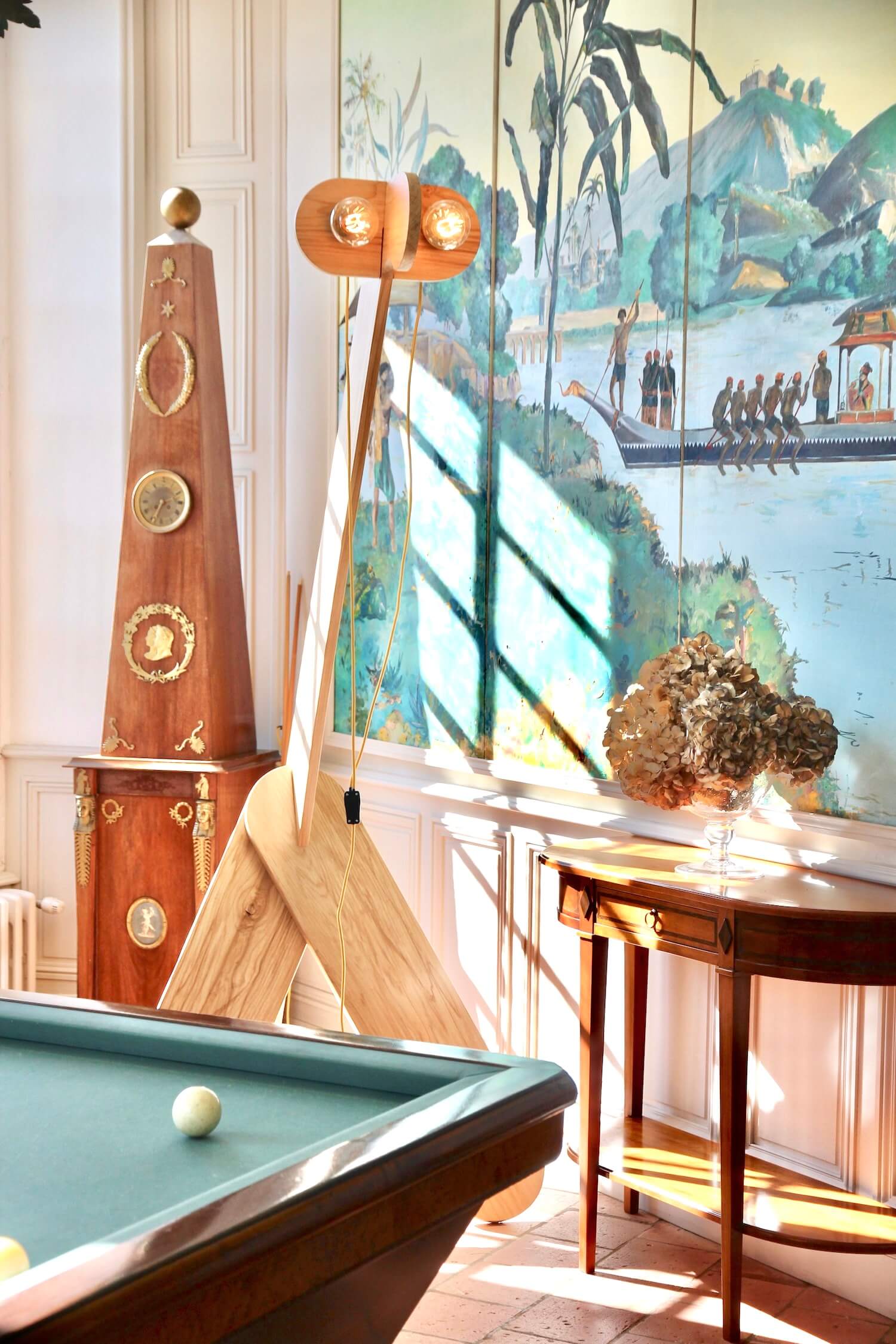 lampadaire de designer en bois massif fabrique en france dans une piece chic et raffinée avec un billard et une fresque
